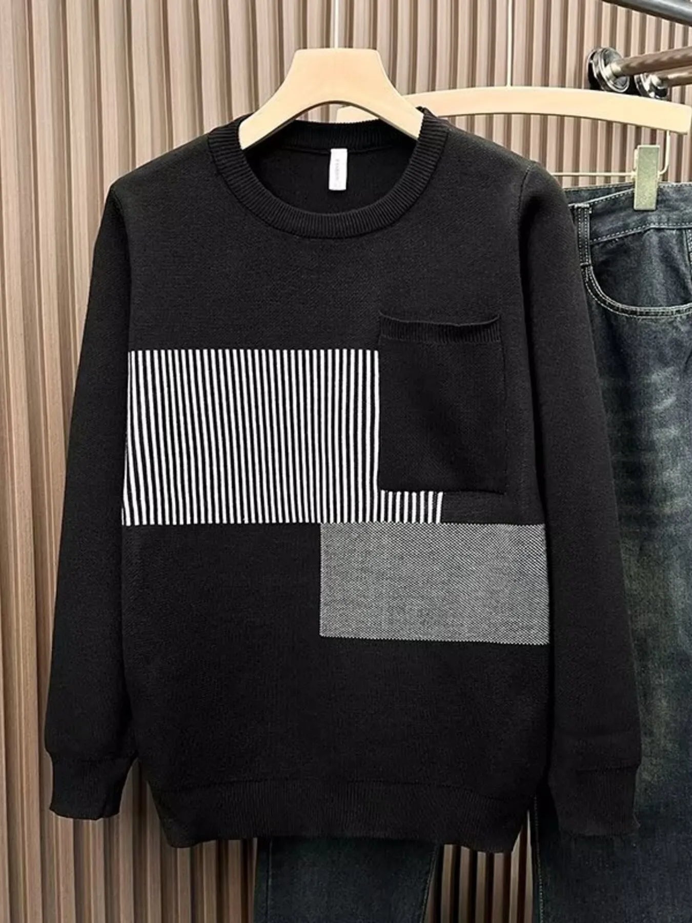 Men's black long sleeve sweater with striped and textured block details and a chest pocket.