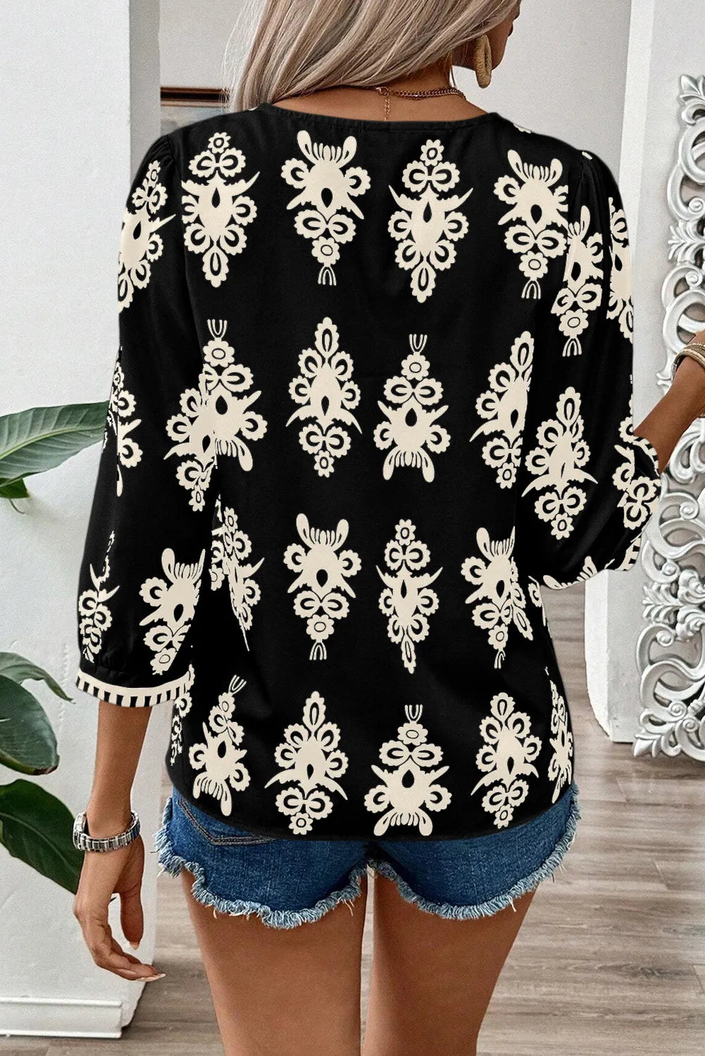 Black V-neck blouse with allover cream embroidery and contrast trim cuffs.