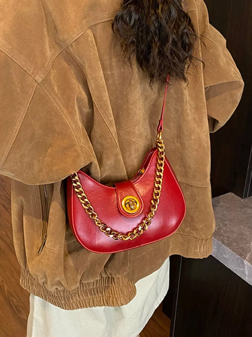 Crescent mini shoulder bag in wine red with gold chain accent and turn-lock closure.