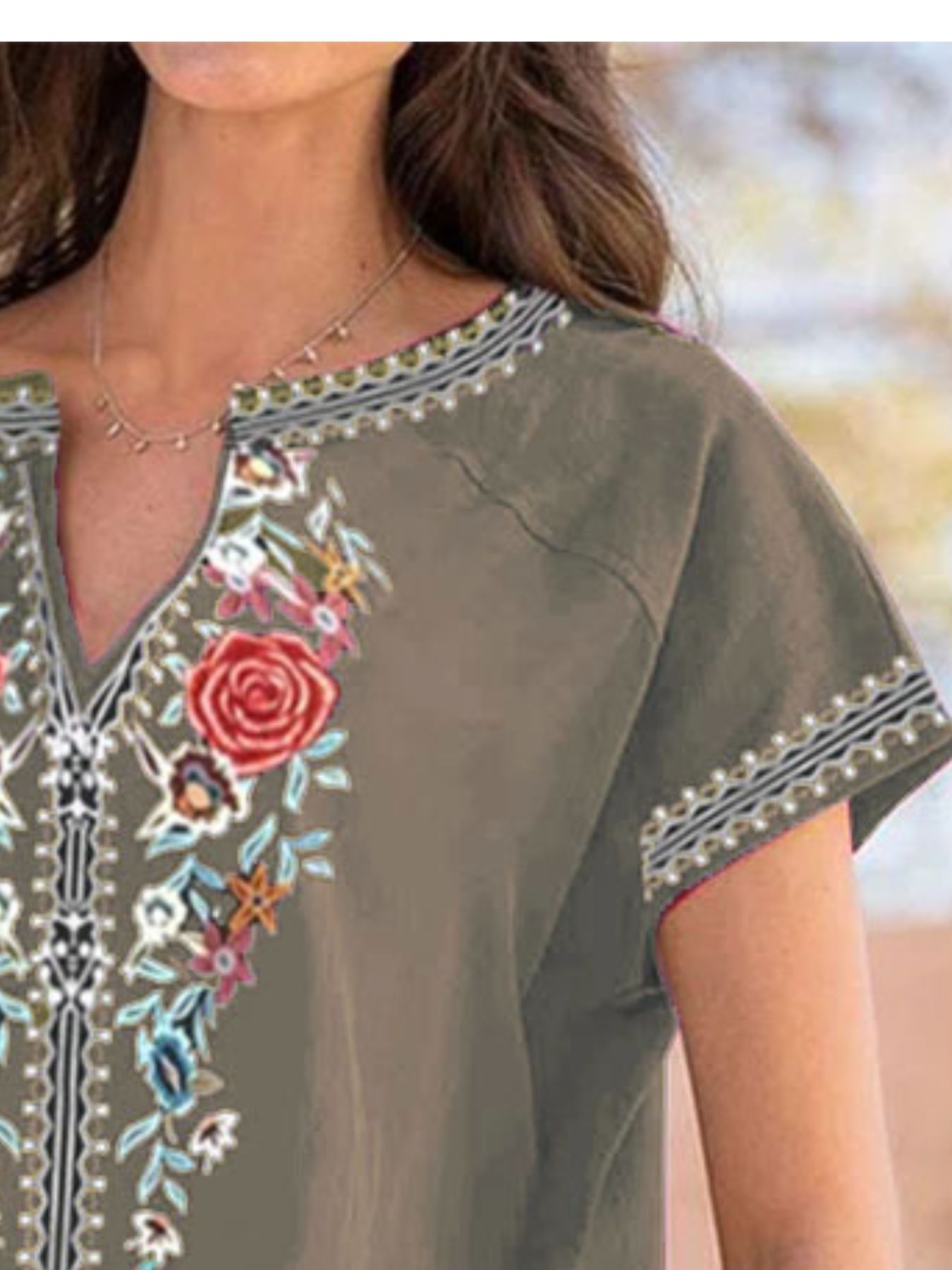 Army green blouse with floral embroidery and notched neckline.