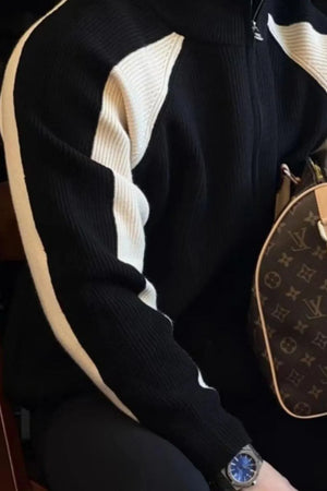 Black ribbed zip-up track jacket with white contrast panels on sleeves and chest.