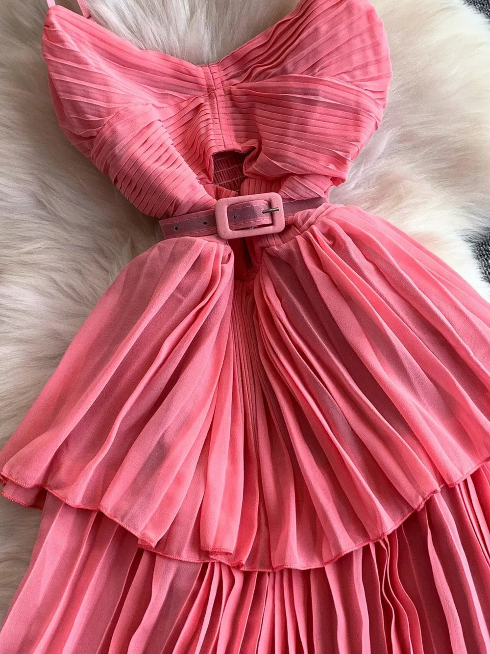 Pink pleated midi dress with spaghetti straps and a matching belt.