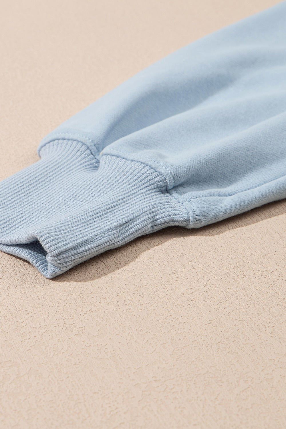 Light blue sweatshirt sleeve detail with ribbed cuff and stitching