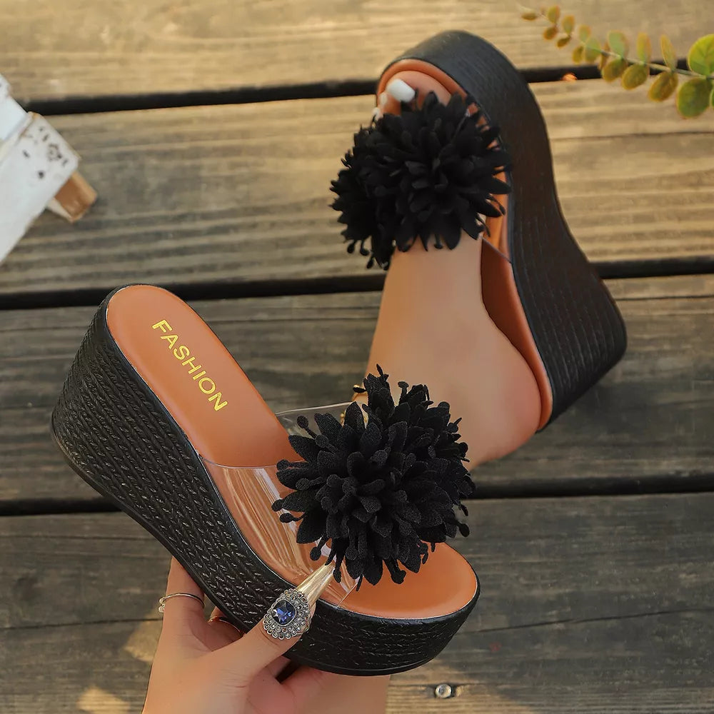 Black wedge sandals with clear straps and fluffy pom-pom detail.