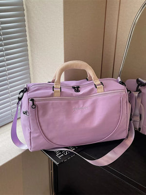 Purple duffel bag with adjustable strap and tan handles, featuring a subtle embroidered logo.