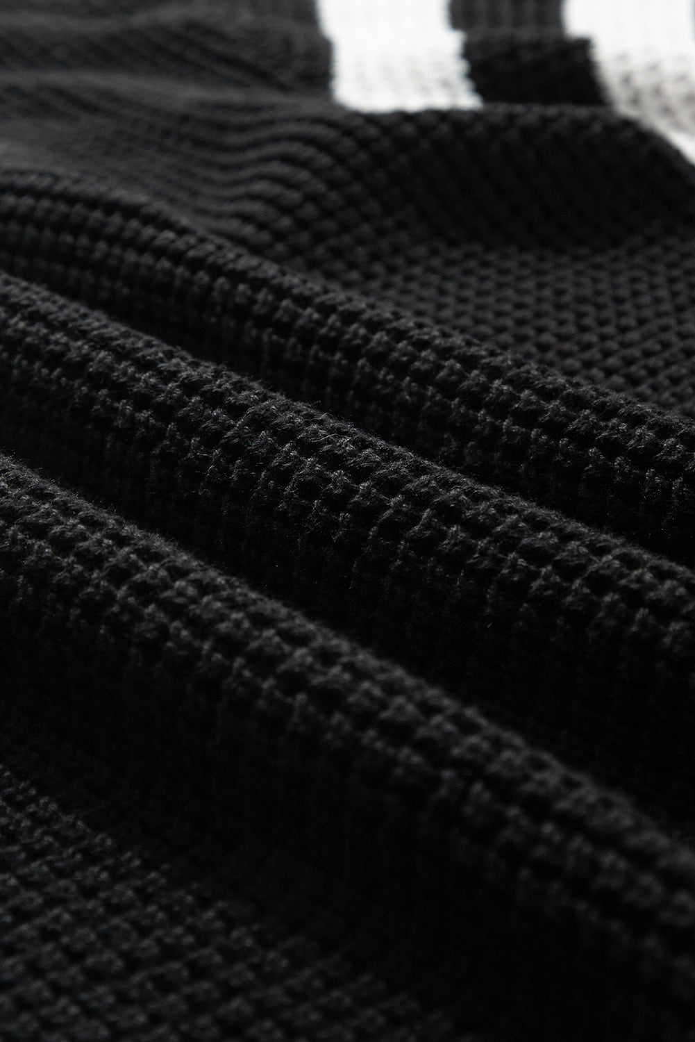 Black knit turtleneck sweater with checkerboard and stripe sleeves