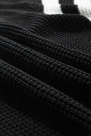 Black knit turtleneck sweater with checkerboard and stripe sleeves