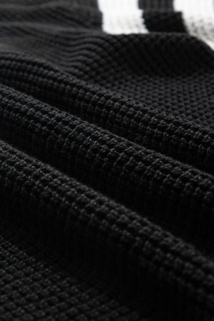 Black knit turtleneck sweater with checkerboard and stripe sleeves