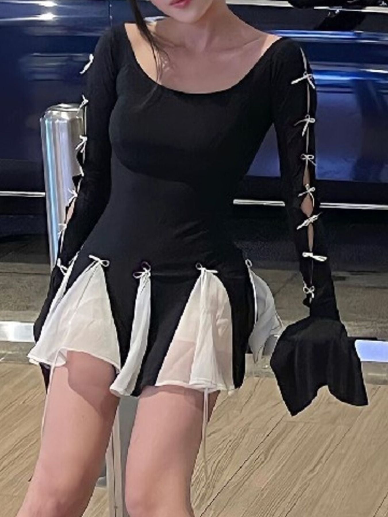 Black mini dress with bowknot details on sleeves and skirt, featuring sheer white accents.