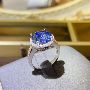 Silver cocktail ring with large blue sapphire and diamond halo.
