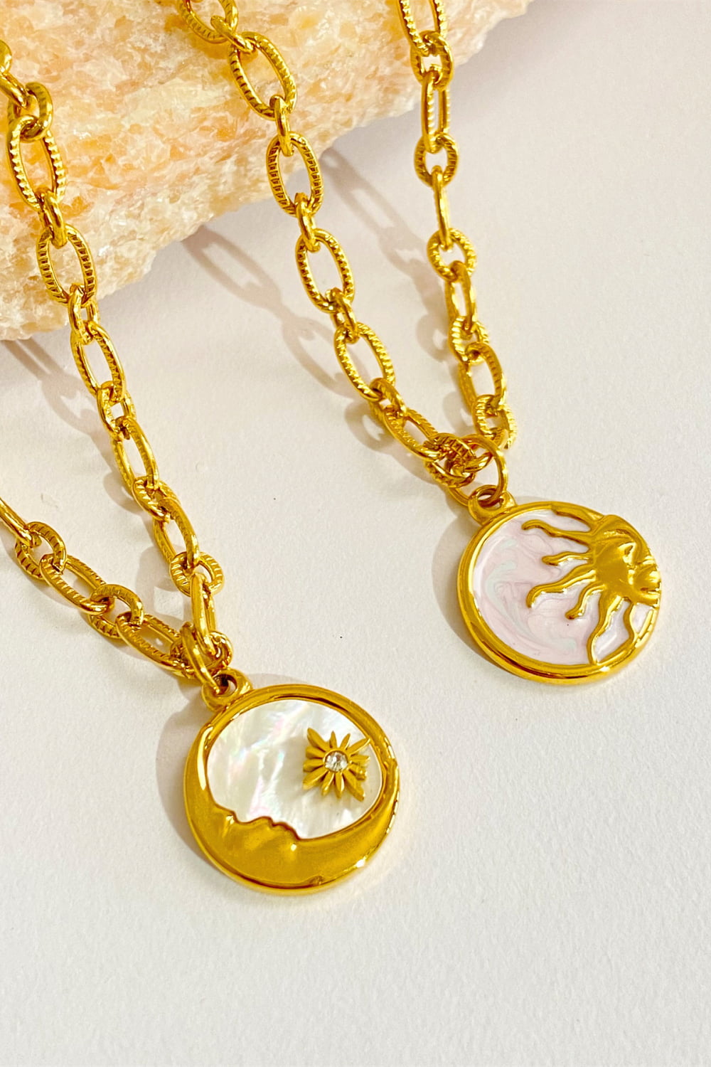 Celestial charm necklaces in gold-plated metal with sun and moon pendants.
