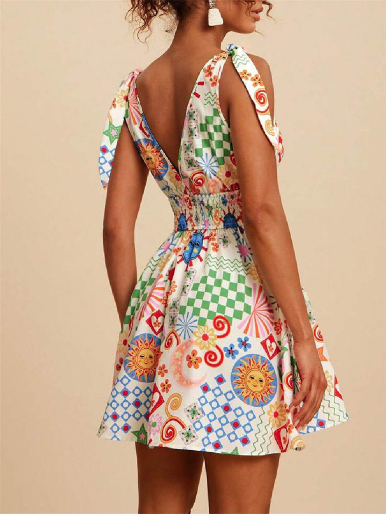Mini dress with tie straps, V-neck, smocked waist, and a playful sun, moon, and checkered print.