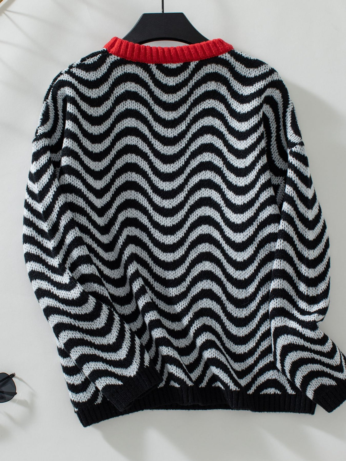 Black and white wavy stripe knit sweater with red contrast collar.