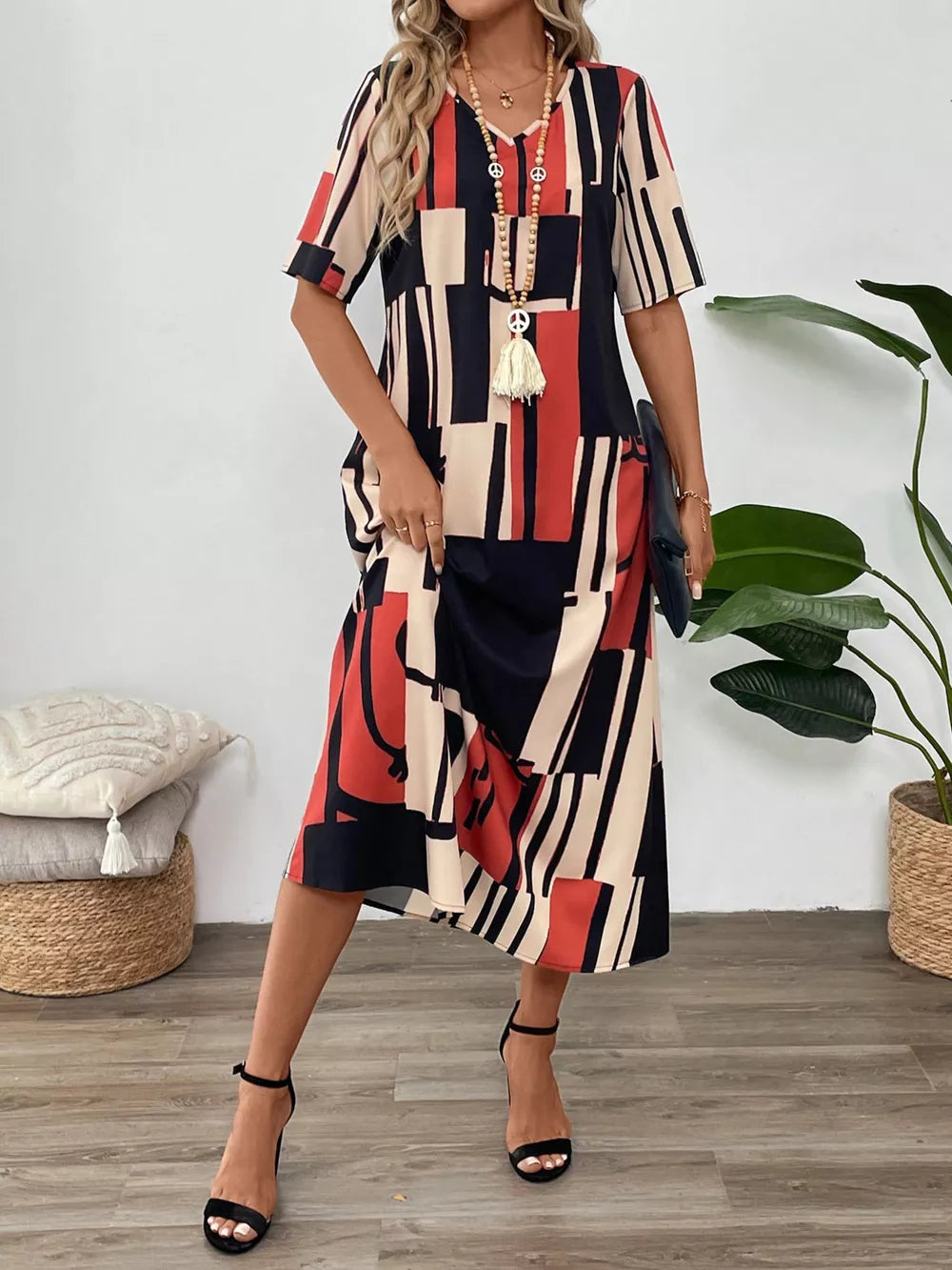 Geometric V-neck midi dress in dark blue, red, and beige with short sleeves and a relaxed fit.