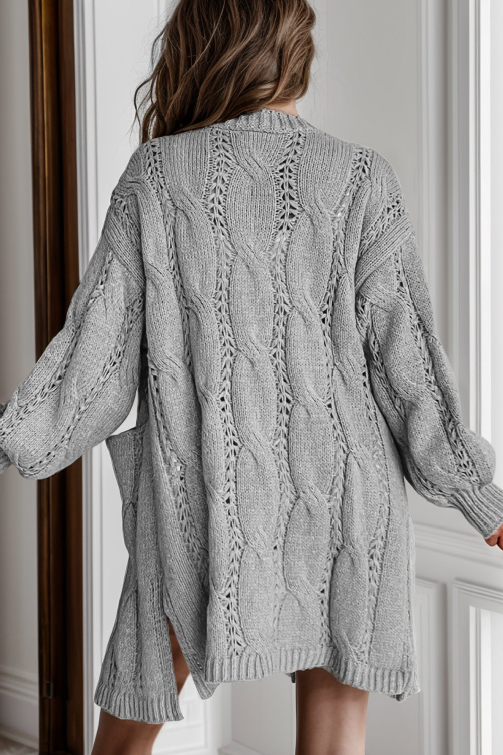 Light gray cable knit open-front cardigan with pockets and openwork details.