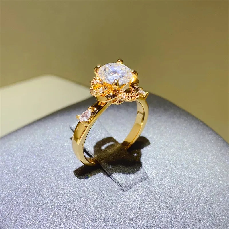 Gold floral halo moissanite statement ring with pear cut accent stones.
