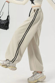 Beige wide-leg sweatpants with black side stripes and drawstring waist.