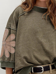 Mineral wash green cotton sweatshirt with a pink flower patch on the sleeve.