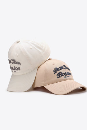 Two baseball caps, one tan and one ivory, with embroidered "Bean Town Boston" text.