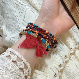 Beaded tassel stacked bracelet set with red tassels and colorful beads.