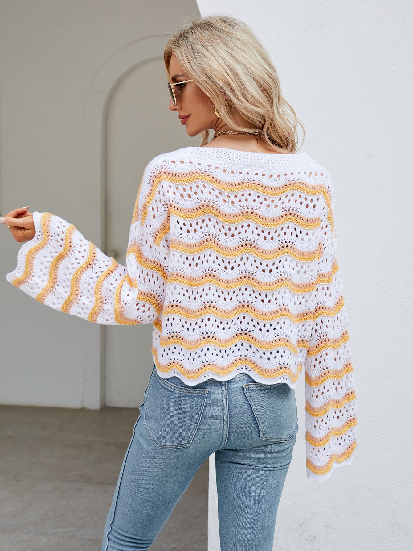 Scalloped crochet crop sweater with orange-red and white wavy stripes, bell sleeves.