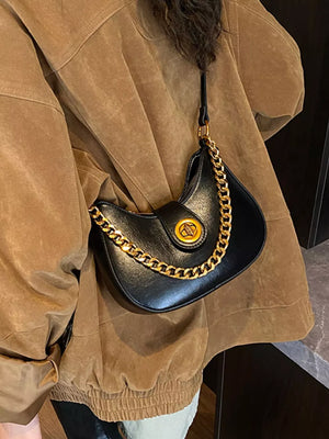 Black crescent mini shoulder bag with gold chain accent and clasp detail.