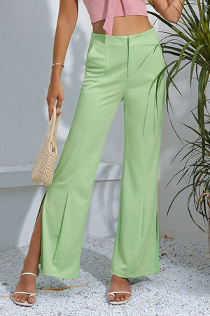 Neon green tailored trousers with high waist and split hems.