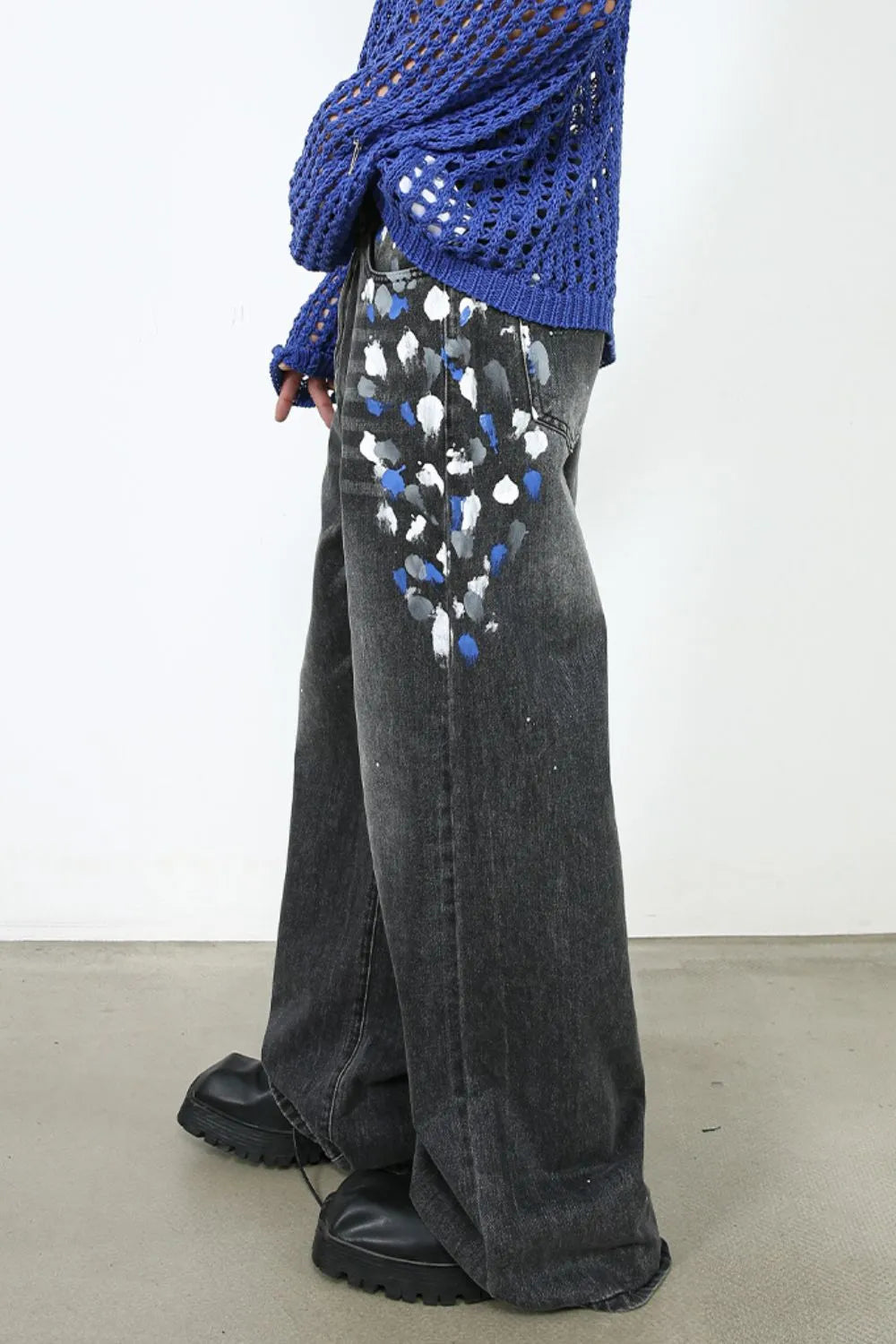 Dark wash flare jeans with painterly blue, white, and grey splatters on the front pockets.