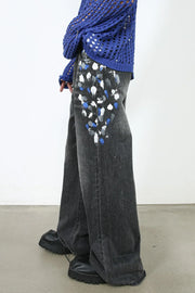 Dark wash flare jeans with painterly blue, white, and grey splatters on the front pockets.