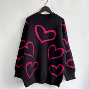 Black acrylic knit sweater with a bold pink heart outline pattern.