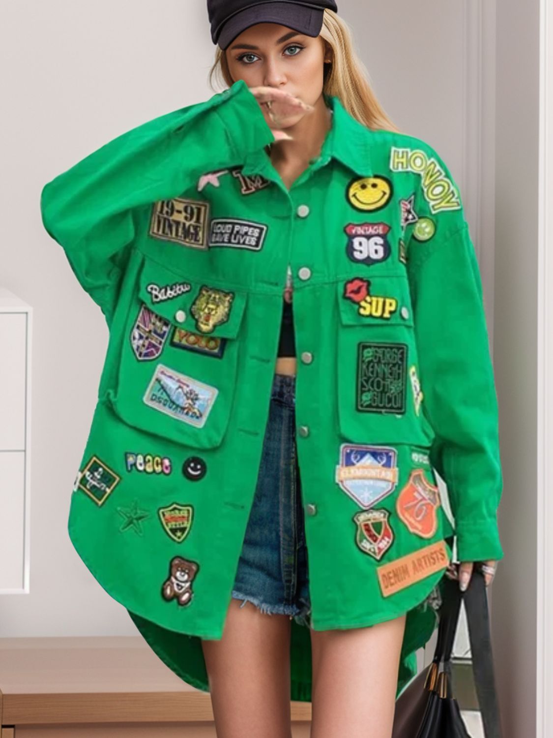 Green denim trucker jacket with embroidered patches, oversized fit, buttoned front, and chest pockets.