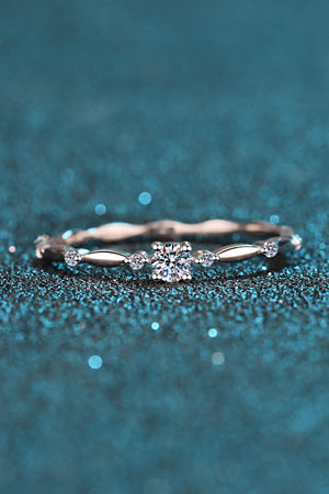 Delicate silver band ring with a central diamond and small accent stones, scalloped detail.