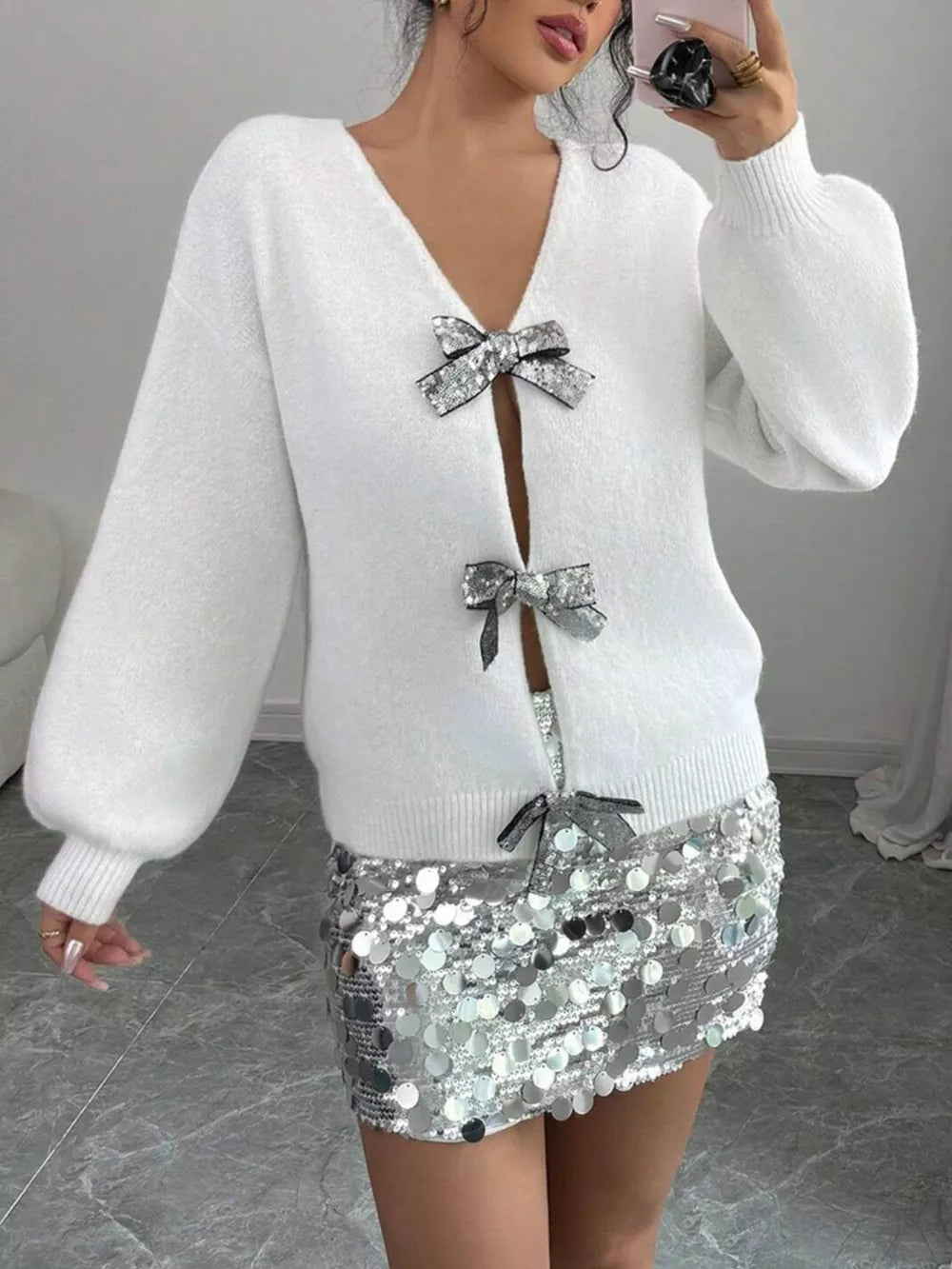 White knit cardigan with sequin bow embellishments and balloon sleeves.