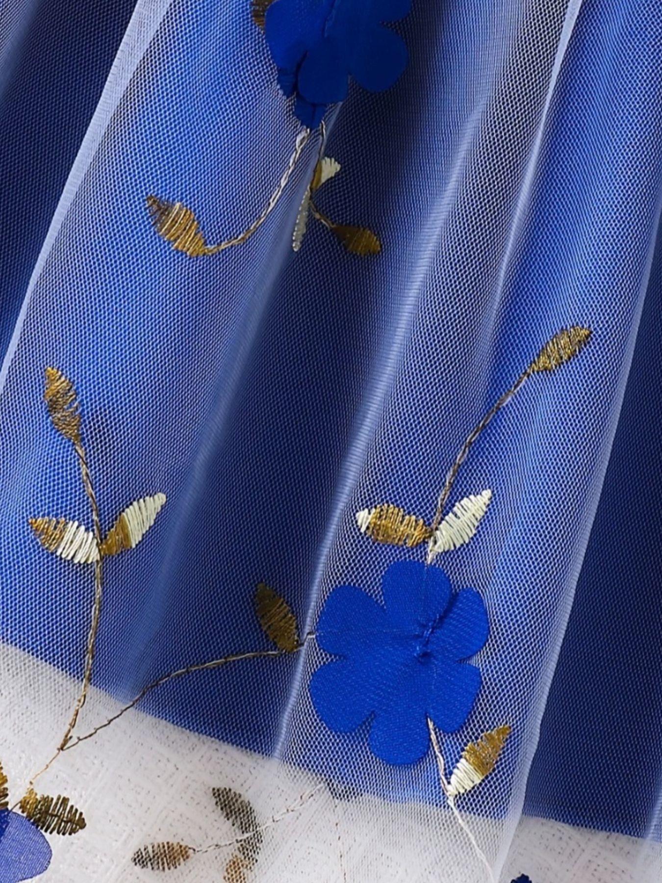 Toddler dress with blue floral embroidery and gold leaf accents on white tulle overlay.
