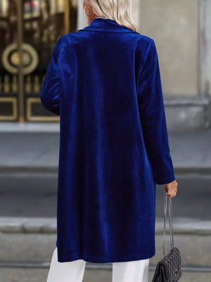 Elegant longline trench coat in dark blue velvet with lapel collar and buttoned front.