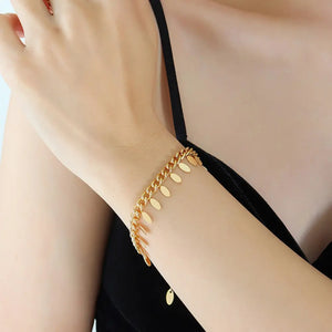 Gold oval link bracelet with dangling charms on a woman's wrist