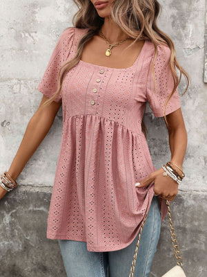 Pink eyelet babydoll top with square neck, puff sleeves, and decorative buttons.