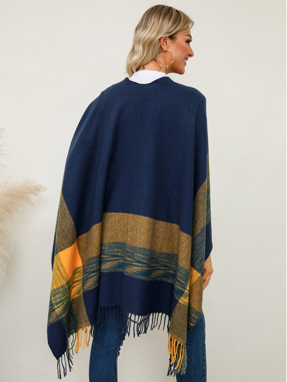 Navy asymmetric plaid cape with fringe and striped detail, worn with jeans.