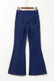 Medium wash denim flare trousers with crossover waist and back pockets.