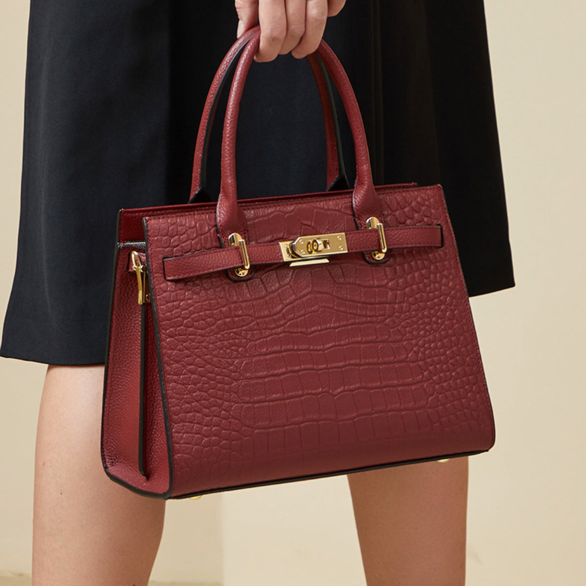 Burgundy crocodile-embossed medium tote handbag with gold hardware and top handles.