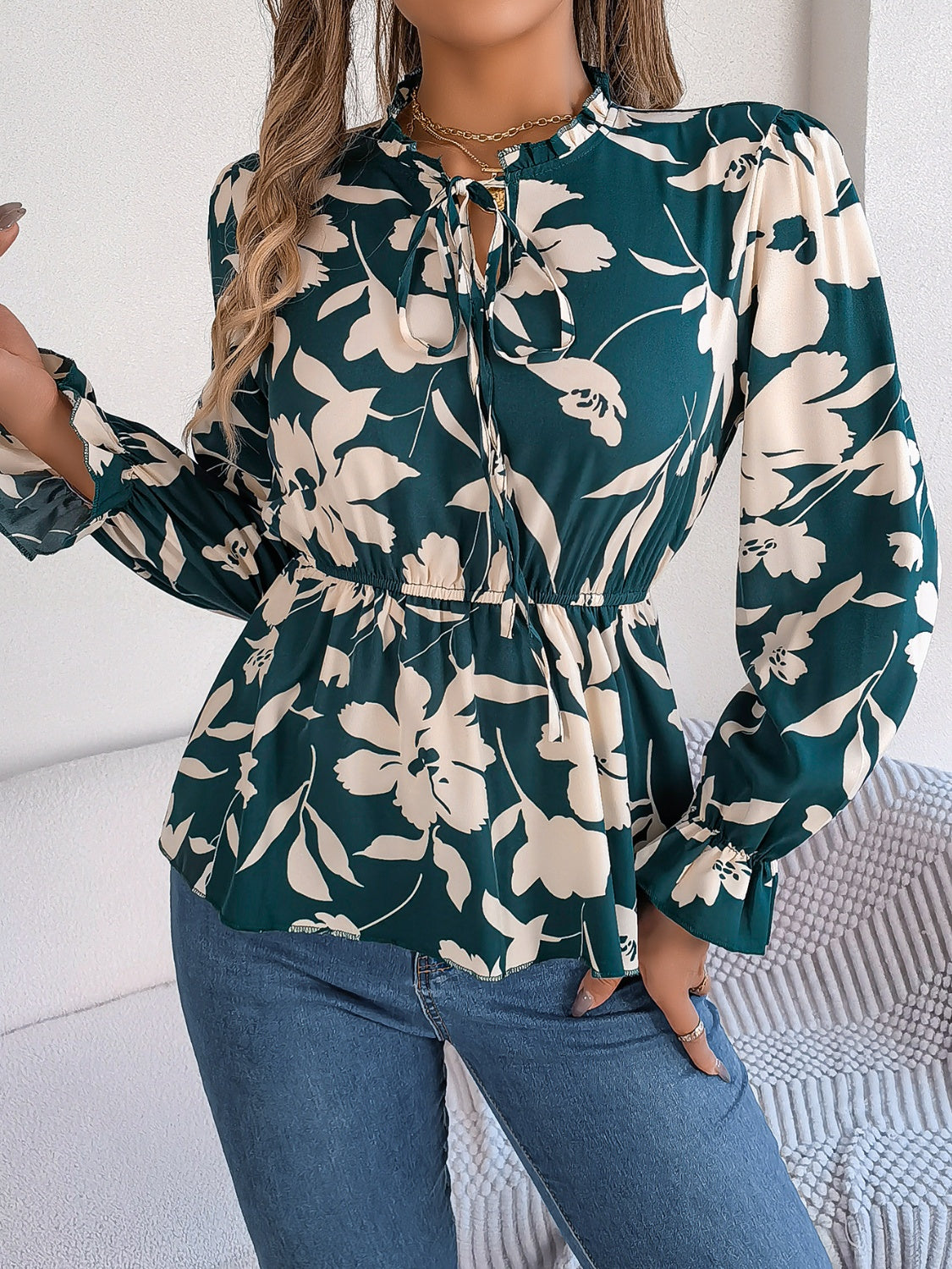 Deep Teal floral peplum blouse with ruffled neck and tie detail, long sleeves.