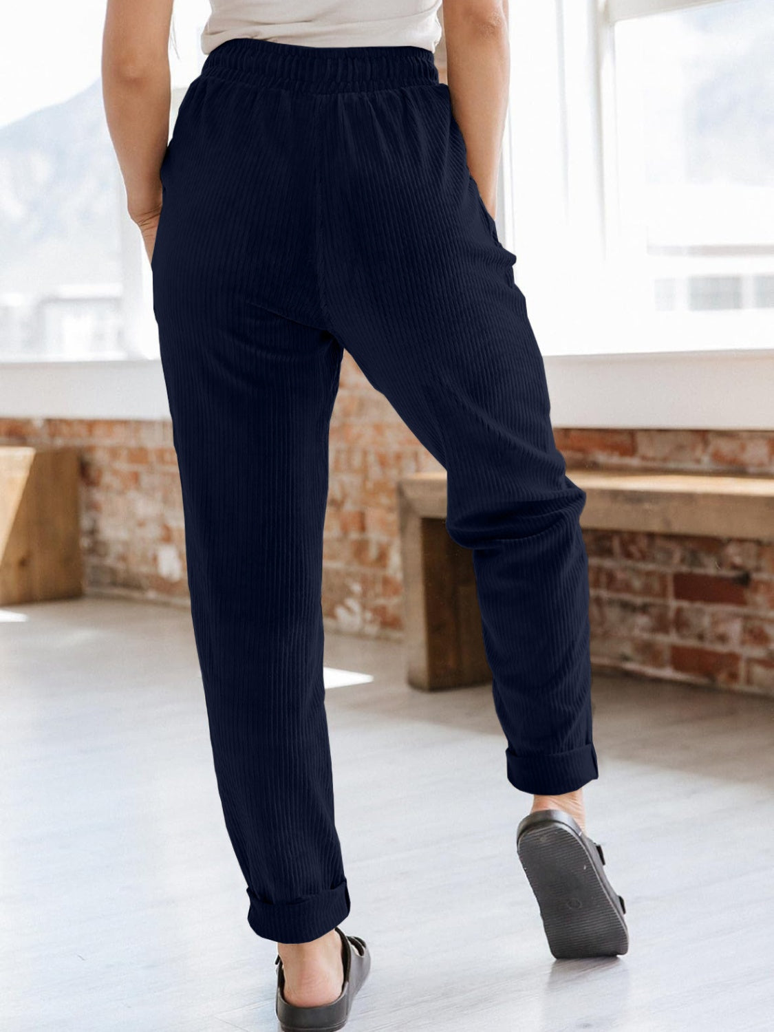 Navy corduroy tapered trousers with drawstring waist and cuffed hems.