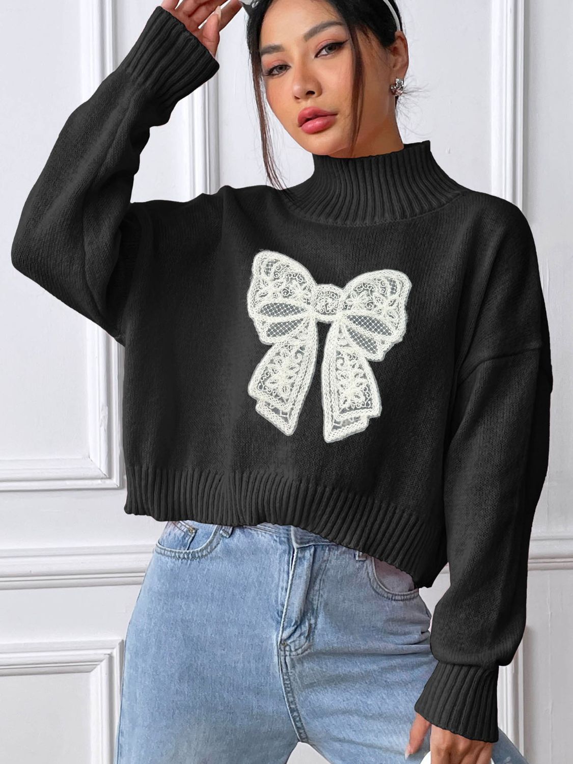 Black turtleneck knit sweater with white lace bow appliqué detail