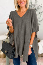 Relaxed V-neck knit poncho top in dark gray with short sleeves and side slits, styled with a black quilted handbag.