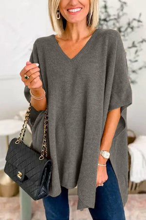 Relaxed V-neck knit poncho top in dark gray with short sleeves and side slits, styled with a black quilted handbag.