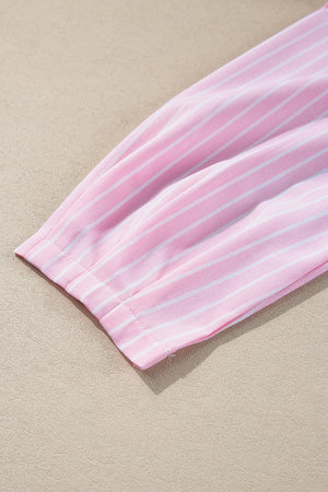 Blush pink striped peplum blouse with a bow detail, close-up on sleeve cuff.