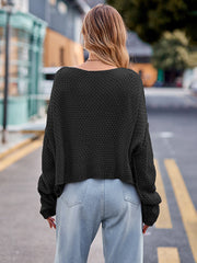 Black acrylic knit sweater with a wide neckline and textured pattern.