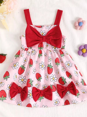 Baby dress in pink with strawberry and daisy print, featuring red bows and straps.