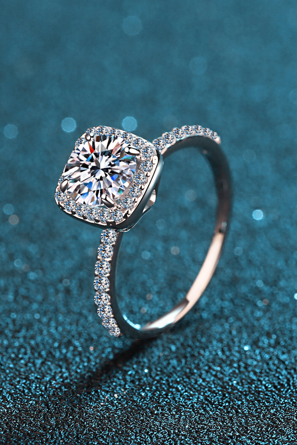 Cushion halo engagement ring in silver with pave band and center stone.