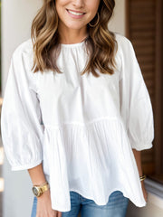 White babydoll blouse with gathered tiers and puff sleeves.